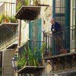 man in blue jacket standing on the balcony - A retiree enjoying time with friends, participating in social activities to avoid loneliness during retirement.
