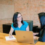 woman in teal t-shirt sitting beside woman in suit jacket - A retiree discussing retirement planning with a financial advisor, evaluating the pros and cons of professional financial advice