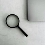 Magnifying glass sits near a laptop on a table