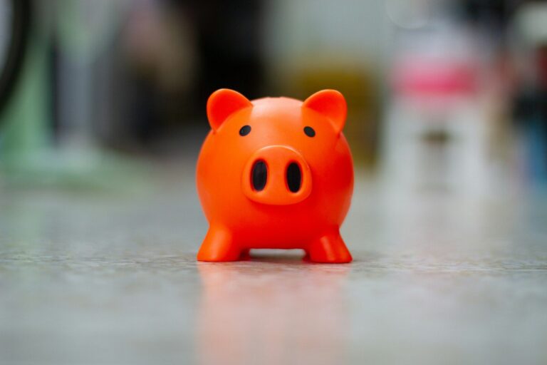 A small orange piggy bank sits on a surface