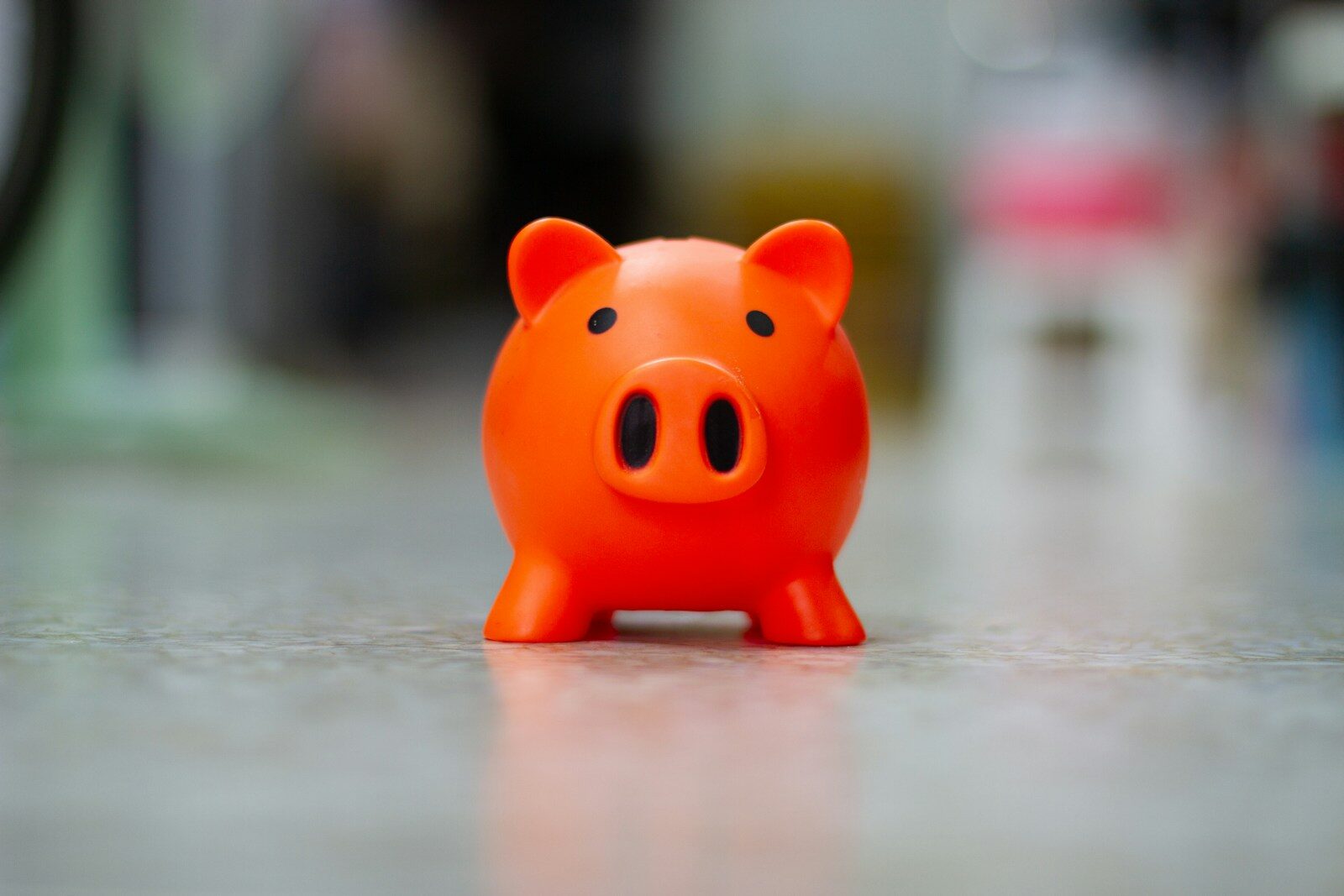 A small orange piggy bank sits on a surface