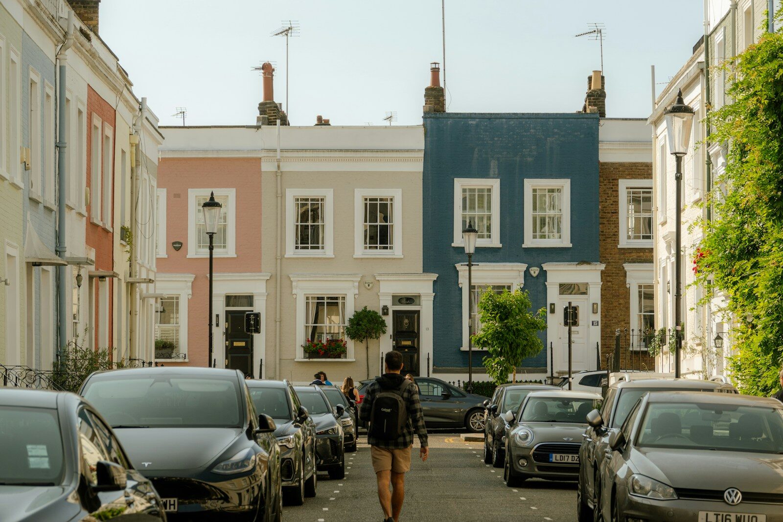 A person walking down a street lined with parked cars