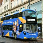 A blue double decker bus driving down a street