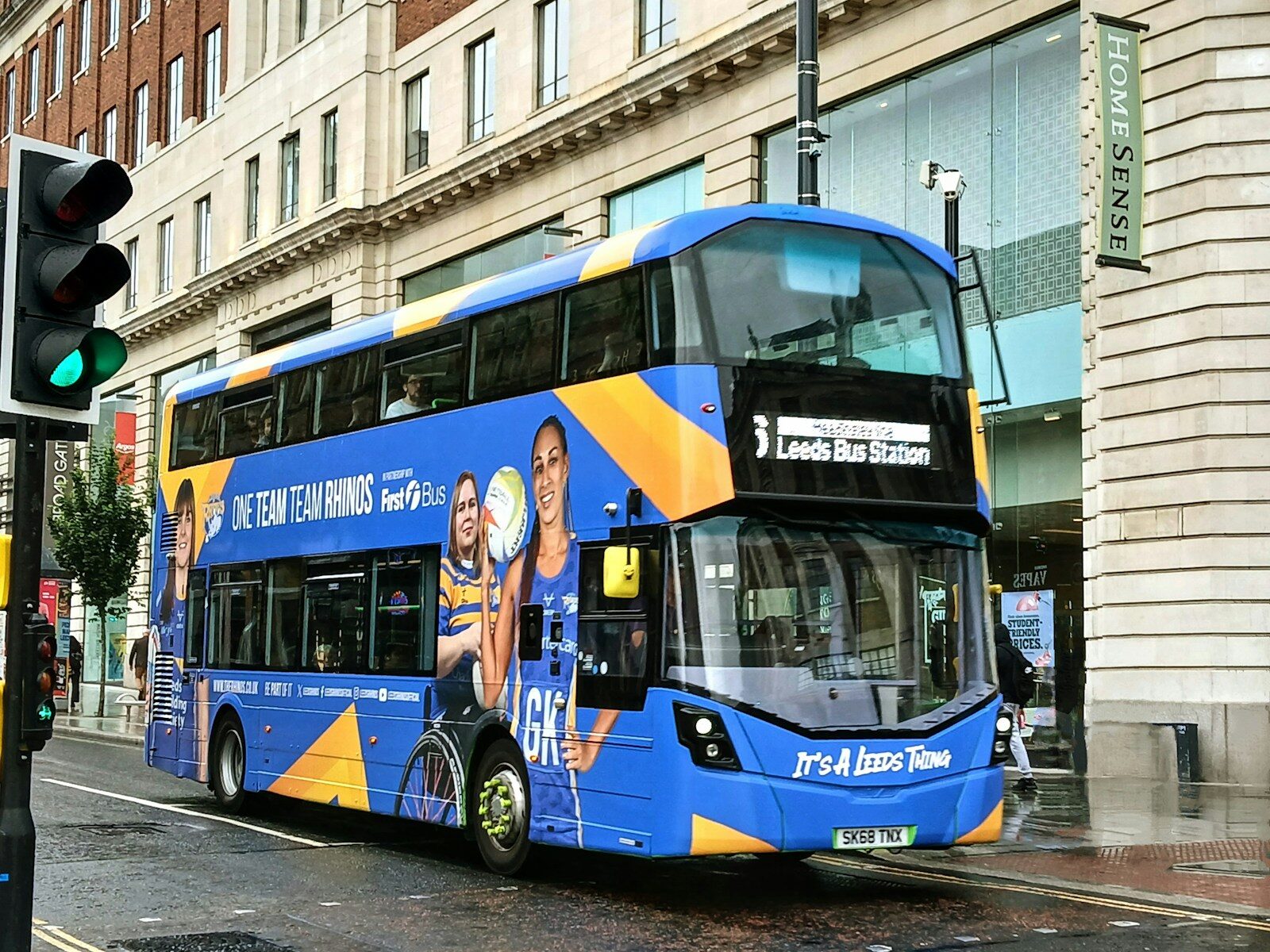 A blue double decker bus driving down a street
