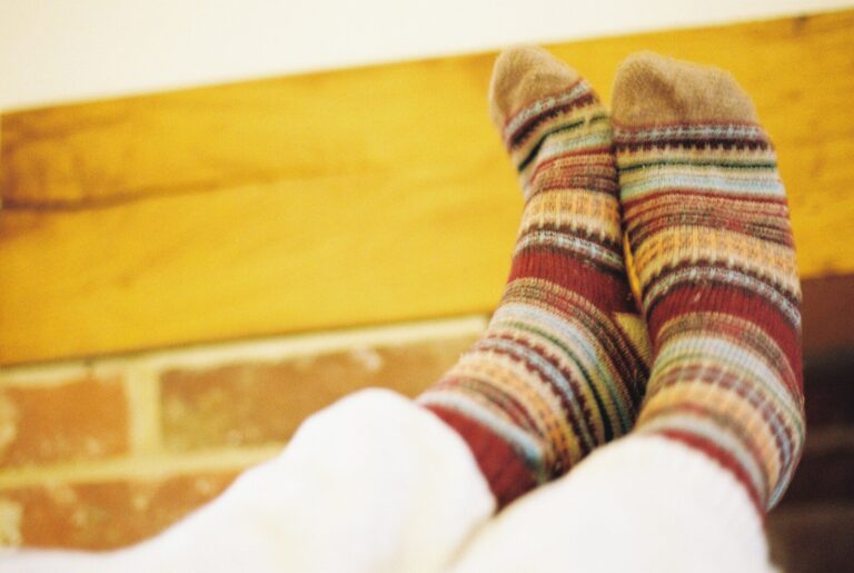 Striped woollen socks against a wooden beam and brick wall